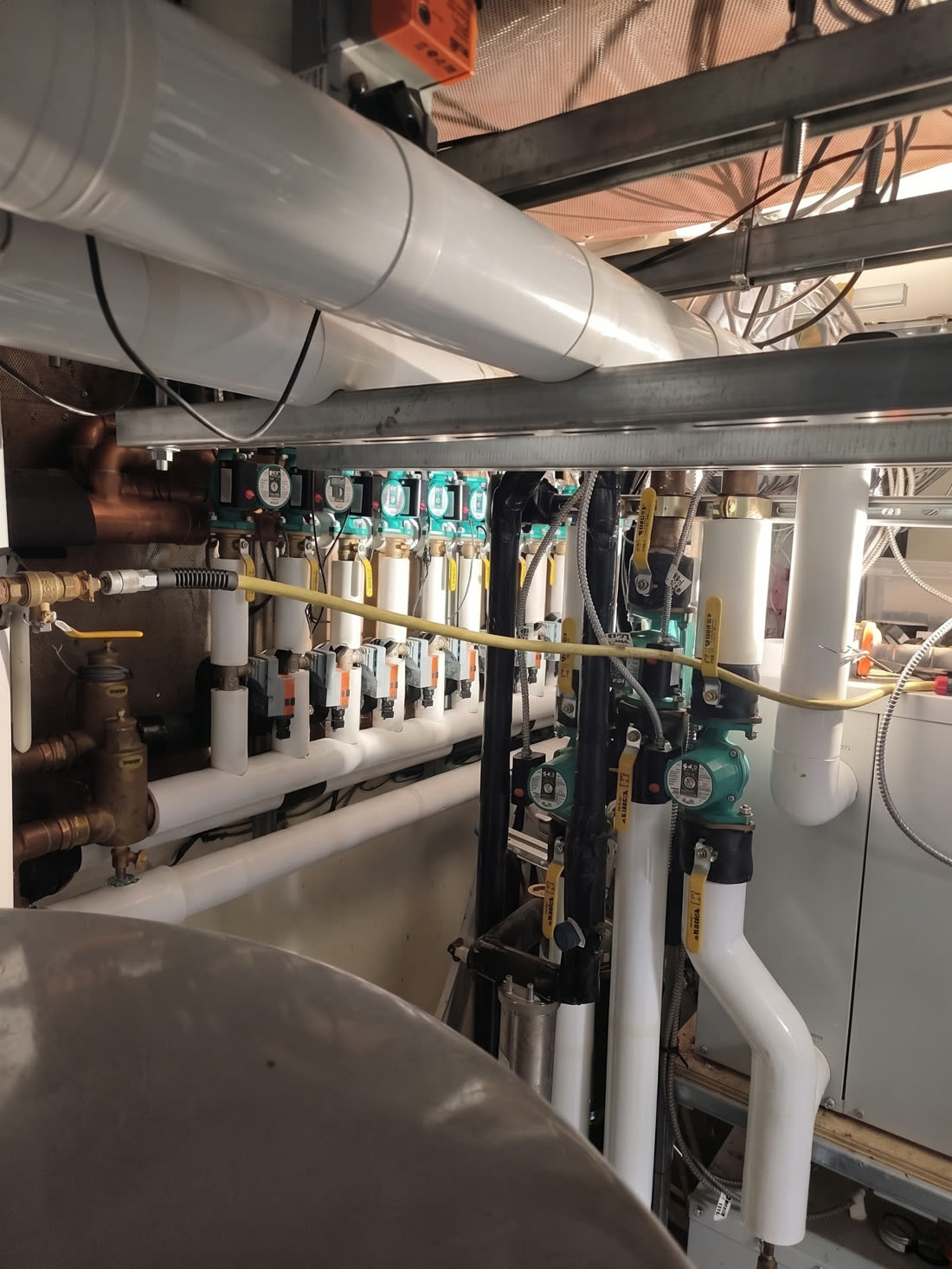 Circulator pumps, insulated pipes and valves in a mechanical room (retouched photograph)